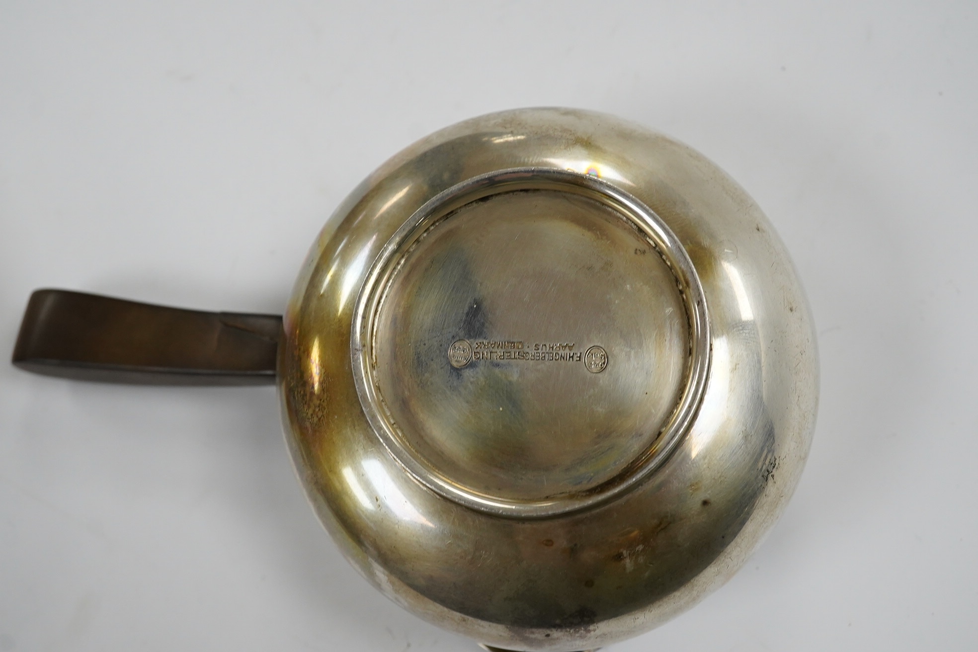 A Danish sterling saucepan, with wood handle, by F. Hingelberg, diameter 95mm and a pair of French pierced plated serving tongs. Condition - poor to fair
